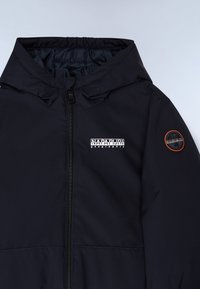 Veste marine sombre avec fermeture éclair, capuche élastique et deux logos : un sur la poitrine en blanc et un sur la manche en orange et noir.