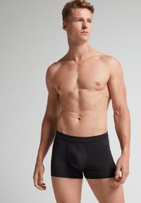 Svarta boxerkalsonger i mjukt tyg, med en tight passform, elastisk midjeband och subtila sömnadsdetaljer som framhäver designens form.