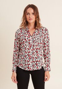 Camicia a maniche lunghe con bottoni in tessuto crema, caratterizzata da un motivo geometrico in rosso, nero e blu navy. Include due tasche sul petto e un colletto classico.