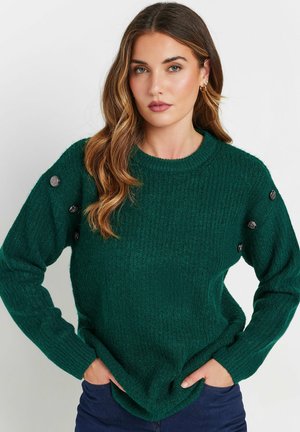 Pull en tricot vert foncé avec une texture côtelée, encolure ronde et boutons décoratifs sur les épaules. Manches longues et coupe décontractée.