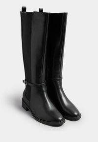 Svarta läderstövlar som går upp till knäna, med elastiska sidor, ett frampart med spänne och en låg blockklack. Slät och glänsande yta.