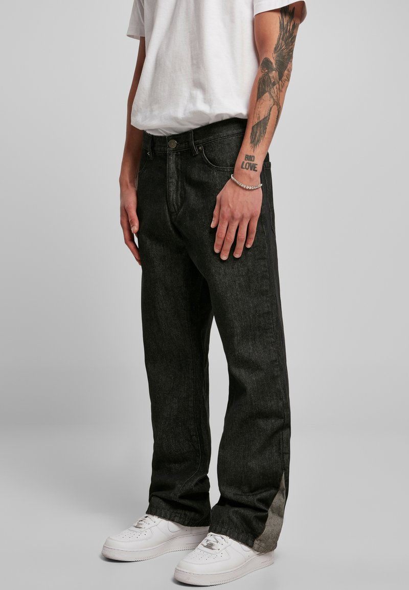 Svarte denim jeans med løs passform, som har en svak falming og kontrastsøm. Kombinert med hvite sneakers og en enkel hvit t-skjorte.