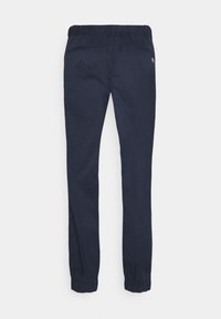 Marinblå joggerbyxor gjorda av ett slätt material, med elastisk midja, avsmalnande ben och två bakfickor med en subtil logotypdetalj.