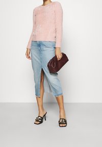 Ljusrosa, fluffig tröja med långa ärmar; blå denim, medellång kjol med mittenskärning och fransad fåll; svarta klackar med guldaccenter; bordeauxfärgad kuvertväska.