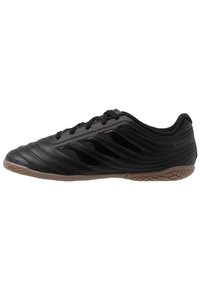 Czarne korki do piłki nożnej Adidas Copa na halę z gumową podeszwą, szyty wzór i trzy błyszczące czarne paski po boku.