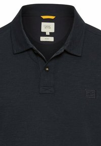 Marine polo skjorte med klassisk krave, to-knaps placket og et lille logo på venstre bryst. Fremstillet af økologisk materiale med en tekstureret overflade.