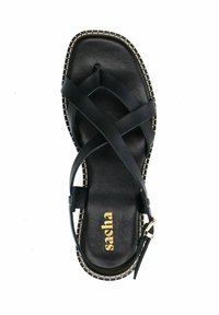 Sandale en cuir noir avec des brides croisées et une boucle, présentant une semelle intérieure texturée et des coutures claires contrastées le long de la semelle.