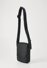 Borsa a tracolla nera in tessuto, di forma rettangolare, con chiusura a zip e superficie testurizzata. Dotata di una larga tracolla regolabile.