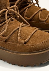 Hnedé semišové ankle boots s krížovými šnúrkami, hrubou gumovou podrážkou a štruktúrovaným povrchom, s vankúškovou platformou.