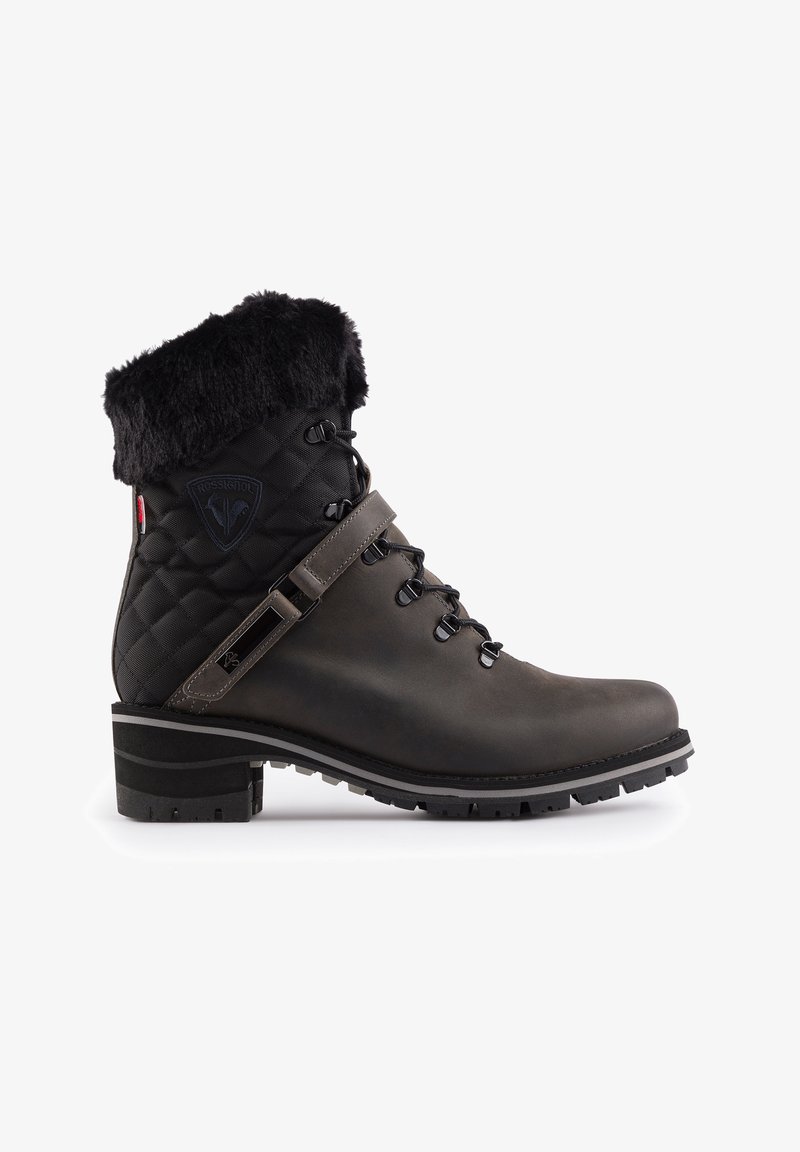 Bota impermeable en negro y gris con parte superior de textil acolchado, cuello de piel sintética, cordones en la parte delantera y suela de goma robusta. Presenta un detalle de correa.