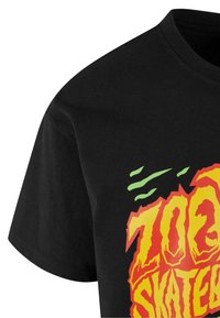 Sort bomulds t-shirt med et levende gul og rød grafisk tekstdesign med grønne accentlinjer. Klassisk rund hals og korte ærmer.