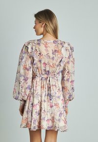 Vestido floral con mangas rizadas, tejido ligero, colores pastel, cintura entallada y un lazo en la parte de atrás.