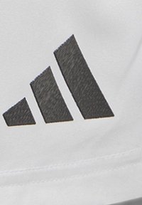Weißes Stoffpatch mit einem schwarzen Logo-Design mit drei Streifen, mit strukturierten Details und sauberen Kanten. Die Nähte sind entlang der unteren Kante sichtbar.