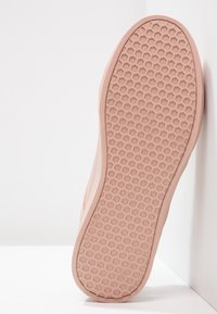 Sula i mjuk rosa gummi med ett bikakestrukturmönster. Lätt upphöjda kanter, slät yta och rundad form.