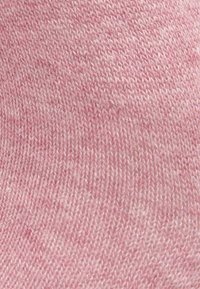 Rosa strikket stoff med en jevn tekstur. Materialet har et konsekvent mønster av sammenvevde tråder, som gir et mykt utseende.