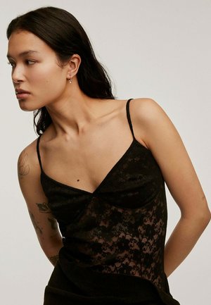 Camiseta de encaje negro con tirantes finos tipo espagueti, que presenta un escote en forma de V y un patrón floral, texturizada con tela en capas.