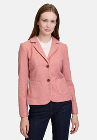 Vaaleanpunainen villasekoitebleiseri, jossa on lovettu kaulus, kaksi etutaskua ja ruskeat napit. Bleiserissä on vartalonmyötäinen malli ja tekstuuri.