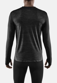 Musta pitkähihainen urheilupaita, jossa on teksturoitu vartalo ja sileät tummat hihat. Paidassa on pyöreä kaula-aukko ja slim fit -malli.