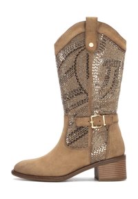 Bota de ante hasta la rodilla en color marrón con un patrón de cortes decorativos, acento de hebilla y tacón de tipo apilado. Textura suave con un diseño estructurado.