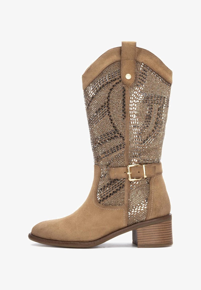 Bota de ante hasta la rodilla en color marrón con un patrón de cortes decorativos, acento de hebilla y tacón de tipo apilado. Textura suave con un diseño estructurado.