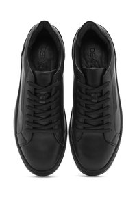 Baskets en cuir noir avec une texture lisse, dotées d'un design à lacets, d'un col rembourré et d'une marque subtile sur la semelle intérieure.