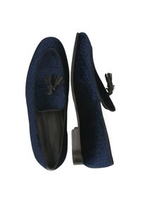 Donkerblauwe loafers met een gestructureerd patroon, afgewerkt met een zwarte kwast aan de voorkant en een lage, stevige hak.