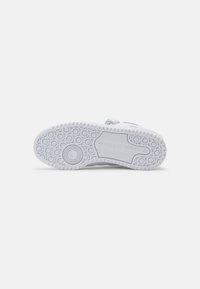 Suela de zapatilla deportiva blanca con dibujos circulares, que presenta goma texturizada, surcos para tracción y un logo grabado.