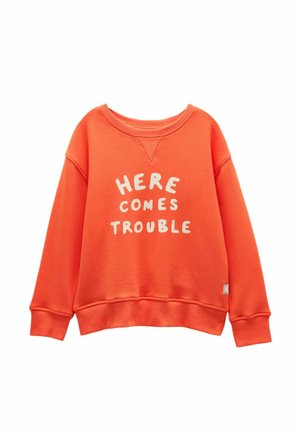 Oranž pikkade varrukatega dressipluus soonikkoes varrukate ja äärega, ees valge tekst "HERE COMES TROUBLE".