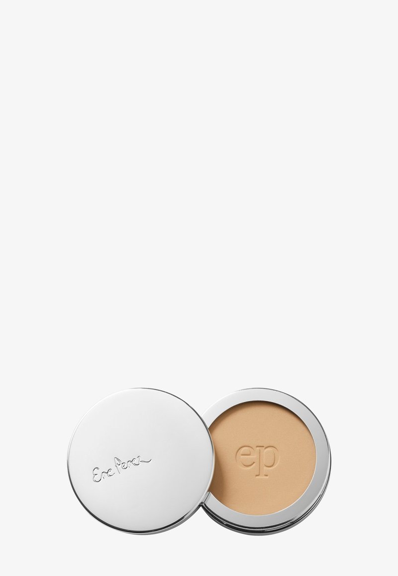 Boîtier rond et compact contenant une poudre crème beige clair, extérieur métallique argenté avec logo embossé, texture lisse à l'intérieur, design à ouverture par clapet.