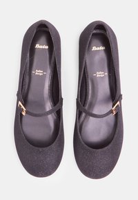 Zapatos Mary Jane negros con textura brillante, punta redonda y una correa delgada que presenta una hebilla dorada; interior negro suave.
