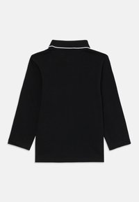 Čierna polokošeľa s dlhým rukávom a golierom, so bielym lemovaním na golieri, s jednoduchou a hladkou textúrou.