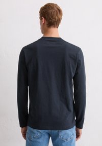 Granatowa koszulka z długim rękawem i okrągłym dekoltem, wykonana z miękkiej bawełny, o luźnym kroju i minimalnej liczbie szwów na plecach.