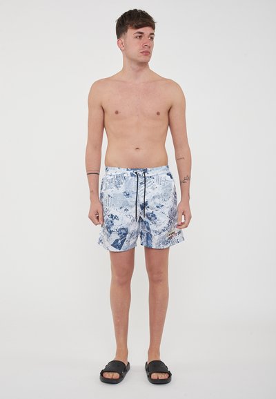 Costumi da bagno bianchi e blu, con una stampa mista di testo e grafica, vita elastica con cordoncino, tessuto leggero.