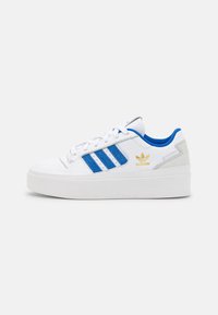 Vita sneakers med blå mockastripes, tjock vit sula och guldlogotypdetalj på sidan. Har snörningsdesign och vadderad krage.