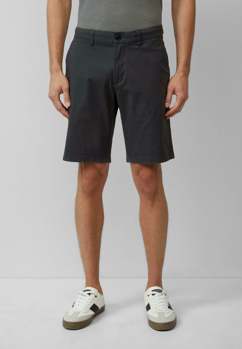 Donkergrijze katoenen shorts met een rechte snit, knoopsluiting, voorzakken en gezoomde randen, gecombineerd met witte sneakers.