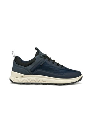 Zapatilla oscura azul con cordones negros, parte superior de malla y cuero, suela beige con un patrón de olas y tirador en el talón.