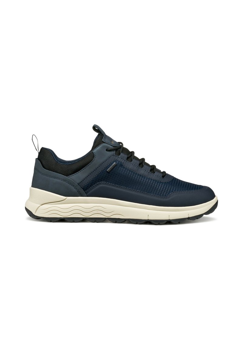Sneaker blu scuro con lacci neri, tomaia in rete e pelle, suola beige con motivo a onde e linguetta sul tallone.