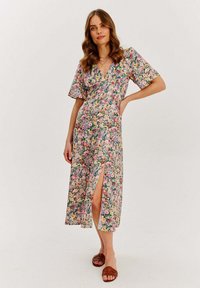 Květinové maxi šaty s krátkými rukávy, se špicatým výstřihem, rozparkem a vícebarevnými květinovými vzory na světlém pozadí.