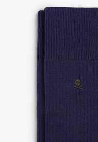 Calze a coste navy realizzate in un tessuto morbido, con un piccolo logo a forma di teschio verde vicino alla parte superiore. Texture liscia con un design classico.