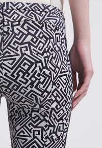 Svartvita geometriska mönstrade leggings med en åtsittande design, som har en hög midja och en jämn yta.