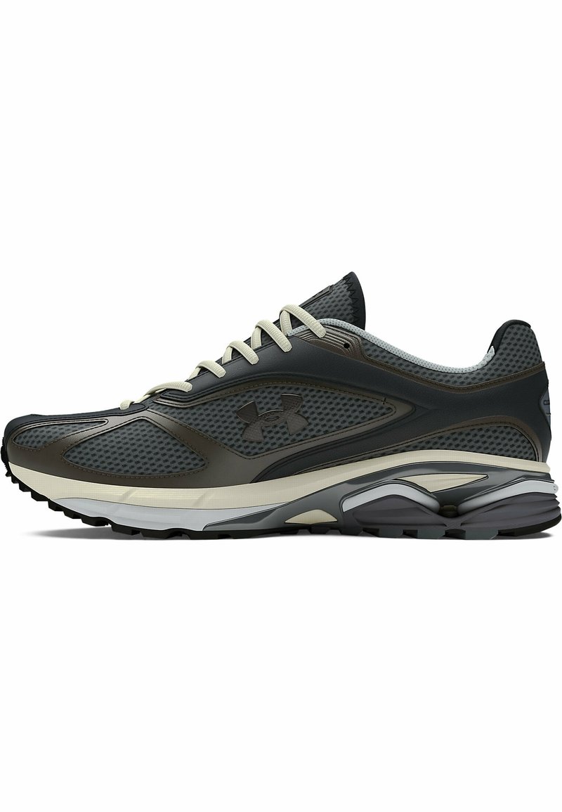 Chaussure de sport Under Armour grise et noire avec lacets beiges, tige en mesh et semelle amortissante conçue pour la course ou un usage athlétique.