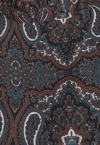 Geweven stof met ingewikkelde paisley-ontwerpen in bruin, turquoise en roomwit, met een donkere achtergrond en een zachte textuur.