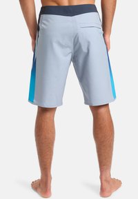 Pánske plavky, svetlošedé s modrým ombré dizajnom, elastický pás a zadná vrecko. Hladký materiál s voľným strihom.