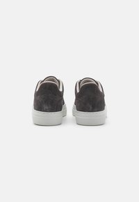 Zapatillas de gamuza gris con un acabado texturizado y suelas de goma blanca, con cuellos acolchados y mínimos detalles de costura.