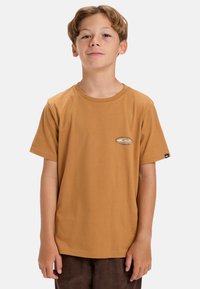 Camiseta de algodón marrón con cuello redondo, mangas cortas y un pequeño parche con el logo en el pecho. Textura suave, corte casual.