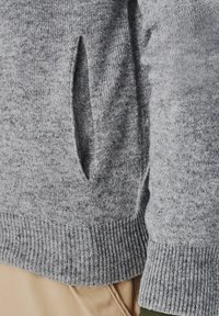 Szary sweter z dzianiny z prążkowanym wykończeniem i boczną kieszenią, wykonany z miękkiego materiału o melanżowej strukturze.