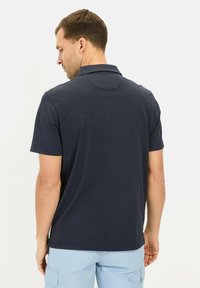 Marineblauw polo-shirt met korte mouwen van een gestructureerde stof, met een klassieke kraag en een comfortabele pasvorm, getoond van achteren.