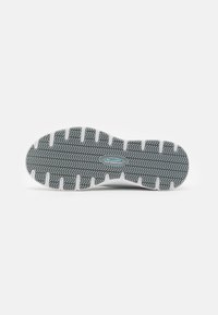Semelle de chaussure en caoutchouc gris avec un motif de semelle en chevron. Présente un design antidérapant et des accents blancs le long des bords.