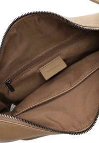 Beige leather bag interior with brown fabric lining, a zippered pocket, and a stitched brand label inside the main compartment.