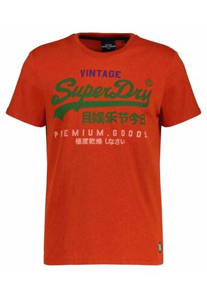 Oranges T-Shirt mit kurzen Ärmeln und dem Schriftzug "Vintage SuperDry Premium Goods" in Blau, Grün und Weiß sowie japanischen Schriftzeichen auf der Vorderseite.